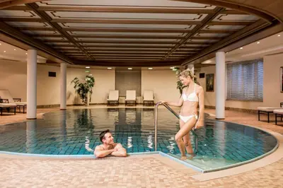 a man and a woman in a swimming pool at Villa Genziana in Selva di Val Gardena