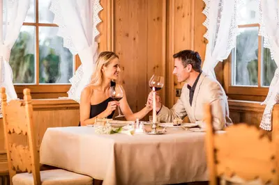 a man and a woman sitting at a table with wine glasses at Villa Genziana in Selva di Val Gardena