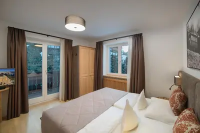 a bedroom with a bed and two windows at Villa Genziana in Selva di Val Gardena