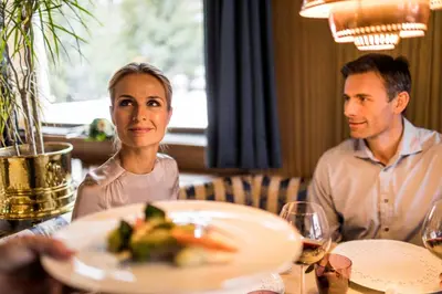 two people sitting at a table with a plate of food at Villa Genziana in Selva di Val Gardena