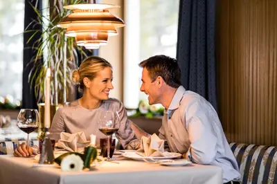 a man and woman sitting at a table with wine glasses at Villa Genziana in Selva di Val Gardena