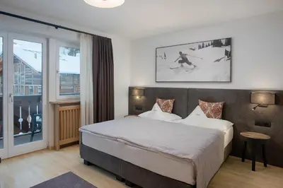 a bedroom with a large bed and a large window at Villa Genziana in Selva di Val Gardena