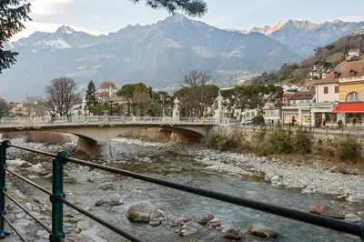 a bridge over a river with mountains in the background at Nel cuore di Merano in Merano