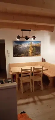 a dining room with a wooden table and benches at Tabià sui Prati- Appartamento bilocale in Falcade