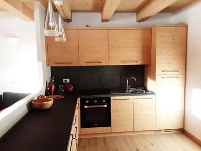 a small kitchen with wooden cabinets and a sink at Tabià sui Prati- Appartamento bilocale in Falcade
