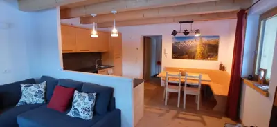 a living room and kitchen with a couch and a table at Tabià sui Prati- Appartamento bilocale in Falcade