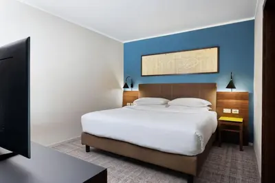 a bedroom with a large bed with a blue wall at Four Points Sheraton Bolzano Bozen in Bolzano