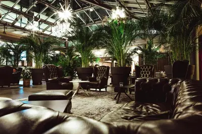 a lobby with leather couches and palm trees at Four Points Sheraton Bolzano Bozen in Bolzano