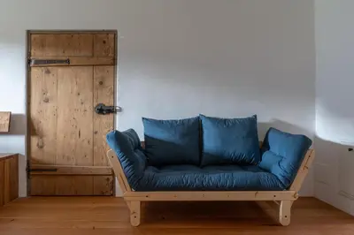 a blue couch in a room with a wooden door at Bauernhof Hof Unternberg in Magrè allʼ Adige