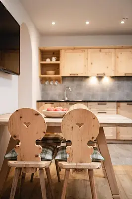 two wooden chairs in a kitchen with a table at Huber unterm Baum in Lagundo