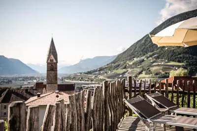 a couple of chairs and a church steeple on a hill at Huber unterm Baum in Lagundo