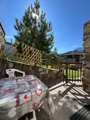 a table and chair on a patio with a pine tree at CASA BERNARD Zortea VANOI cuore verde del Trentino in Canale San Bovo