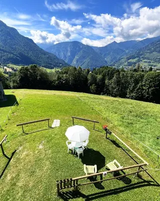 a table and chairs in a field with mountains at CASA BERNARD Zortea VANOI cuore verde del Trentino in Canale San Bovo