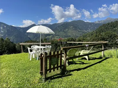 a table and chairs with an umbrella on a hill at CASA BERNARD Zortea VANOI cuore verde del Trentino in Canale San Bovo