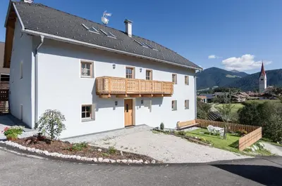 a white house with a wooden balcony on it at Panzenbachhof in Valdaora di Sotto