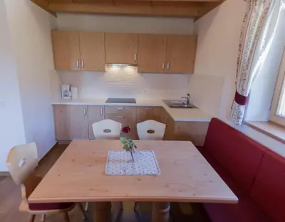 a small kitchen with a wooden table and chairs at Panzenbachhof in Valdaora di Sotto