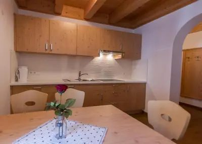 a kitchen with a table with a vase of flowers on it at Panzenbachhof in Valdaora di Sotto