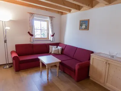a living room with a red couch and a table at Panzenbachhof in Valdaora di Sotto