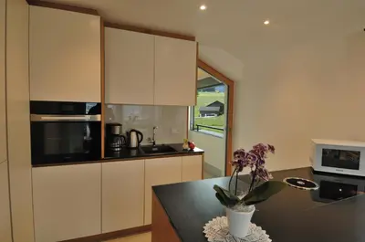 a kitchen with white cabinets and a vase with flowers on a counter at Apartments Helga in Castelrotto