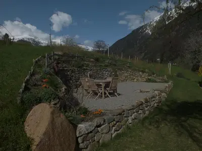 a stone wall with a table and chairs in a garden at Obergereuth Hof 2021 in San Martino