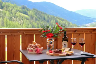 a table with a plate of food and two glasses of wine at Proihof in Funes