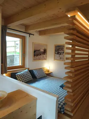 a small room with a bed and a staircase at Tabiá sui Prá - appartamento monolocale Anna in Falcade