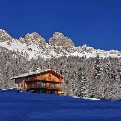 a log cabin in the snow with a mountain at Tabiá sui Prá - appartamento monolocale Anna in Falcade