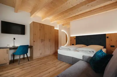 a bedroom with a bed and a desk and a tv at Aria de Munt in San Vigilio Di Marebbe