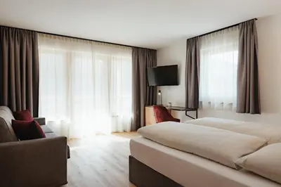a hotel room with two beds and a couch at Aria de Munt in San Vigilio Di Marebbe