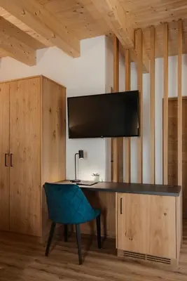 a desk with a blue chair in a room at Aria de Munt in San Vigilio Di Marebbe