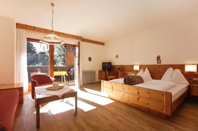 a bedroom with a wooden bed and a living room at Ferienwohnungen St Hippolyt mit Hallenbad in Lagundo