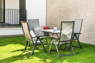 three chairs and a table on the grass at Chalet Miriam in Selva di Val Gardena