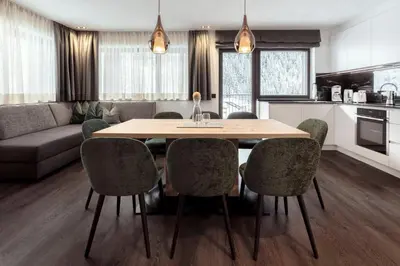 a kitchen and living room with a wooden table and chairs at Chalet Miriam in Selva di Val Gardena