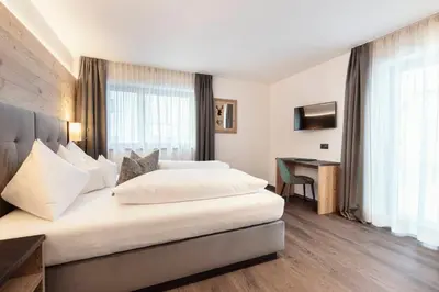 a hotel room with two beds and a desk at Chalet Miriam in Selva di Val Gardena
