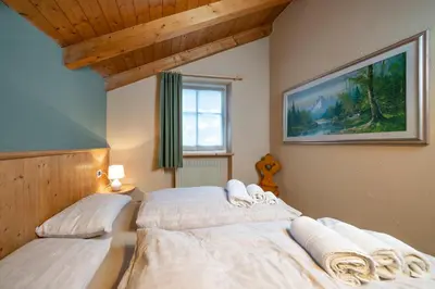 two beds in a bedroom with a painting on the wall at Ciasa Buro - Gimel in Moena