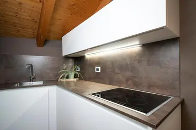 a kitchen with white cabinets and a stove at Ciasa Buro - Gimel in Moena