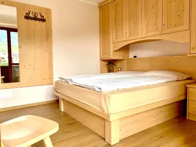 a bedroom with a bed and wooden cabinets at EMARGHE, CASA A MOENA in Moena