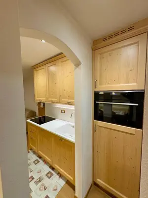 a kitchen with wooden cabinets and a white sink at EMARGHE, CASA A MOENA in Moena