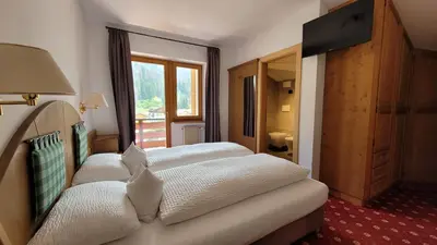 a bedroom with a large bed with wooden walls at Hotel Garni Royal in Arabba