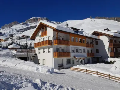 a building in the snow with a mountain in the background at Apartments Alpenroyal Arabba - Check-in at Garni Royal in Arabba