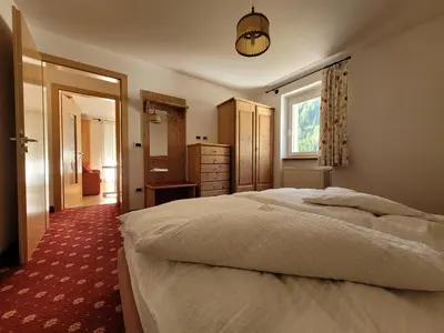 a bedroom with a large bed and a window at Apartments Alpenroyal Arabba - Check-in at Garni Royal in Arabba