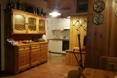 a kitchen with wooden cabinets and a table in it at MirarMonti nel cuore di Pozza con i tuoi animali in Pozza di Fassa