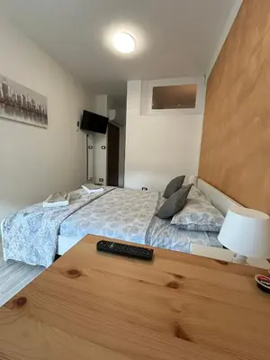 a bedroom with two beds and a remote control on a table at Capri B&B in Bolzano