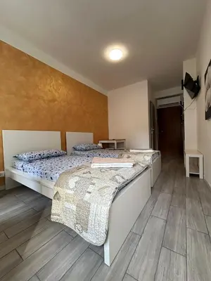 two beds in a room with wooden floors at Capri B&B in Bolzano