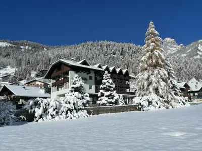 a ski lodge with snow covered trees in front of it at B&B Garni Villa Campitello in Campitello di Fassa