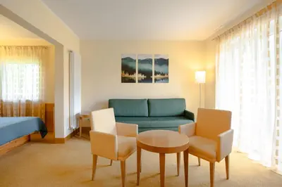 a hotel room with a couch and a table and chairs at B&B Garni Villa Campitello in Campitello di Fassa