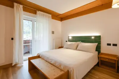 a bedroom with a large bed and a window at B&B Garni Villa Campitello in Campitello di Fassa