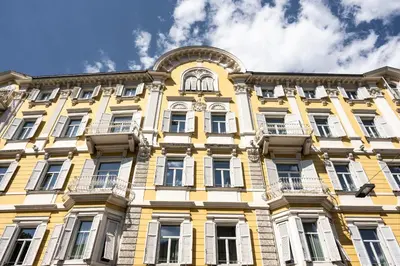 a yellow building with a clock on it at Hotel Stiegl Scala in Bolzano