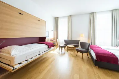 a hotel room with two beds and a table and chairs at Hotel Stiegl Scala in Bolzano