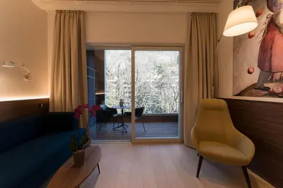 a living room with a blue couch and a chair at Hotel Stiegl Scala in Bolzano